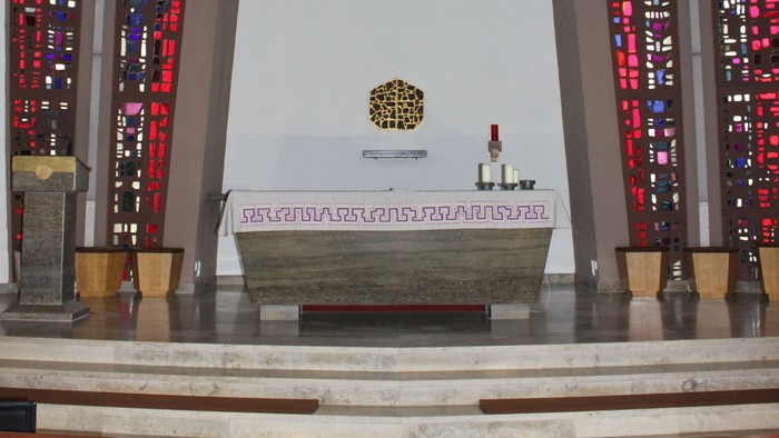 Die Kirche mit Altarraum, Kreuz und buntem Glasfenster