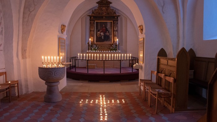 Kapel med lysende kandlelygter og alter med portræt.