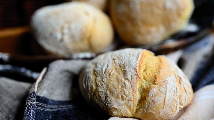 Friskbagte håndværksbrød, der køler af på en bakke med en klud nedenunder.