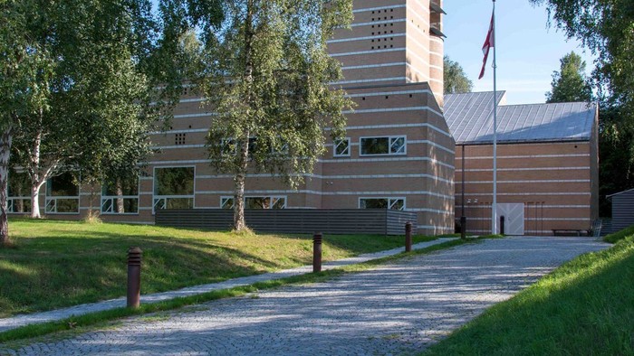 Et moderne bygning med træpanel og flagstang foran