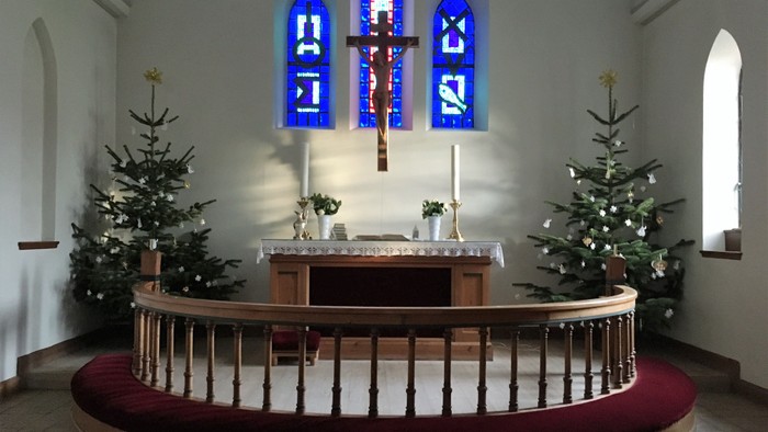 Alter i kirke med juletømmer og blå vinduer