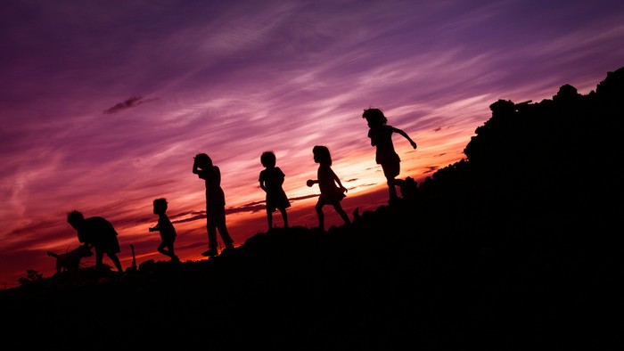 Kinder, die bei Sonnenuntergang auf einem Hügel spielen