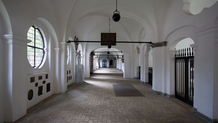 Ein langer, weißer Flur mit gewölbter Decke und Rundbogenfenstern