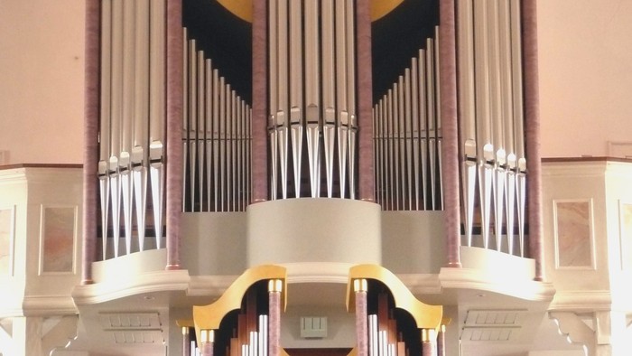 Elegante Pfeifenorgel mit goldenen Akzenten und mehreren Reihen polierter Pfeifen in einem prächtigen Ambiente.