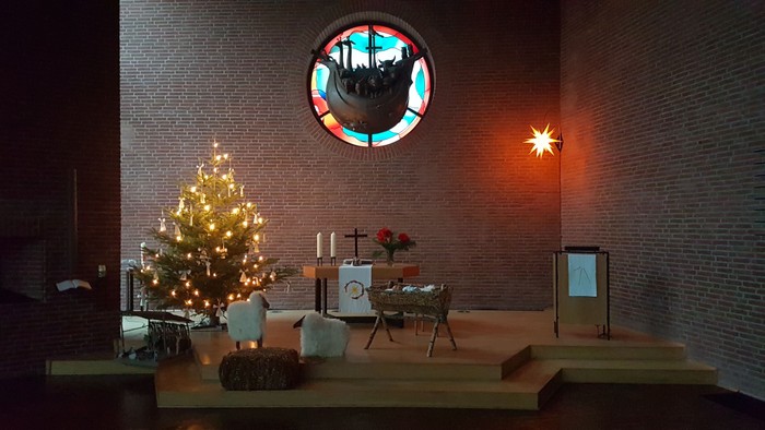 Weihnachtliche Kirchendekoration mit beleuchtetem Baum und Kreuzigungsgruppe