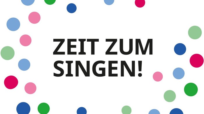 Bunte Punkte umgeben den deutschen Satz „Zeit zum Singen!“ und ermutigen die Menschen zum Singen.