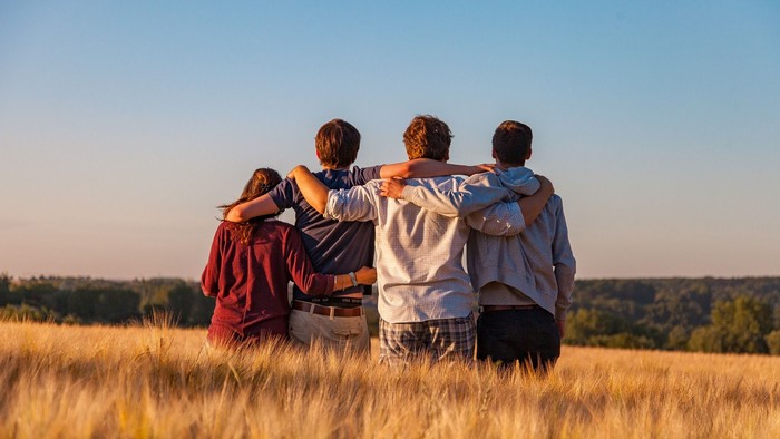 Vier Freunde stehen in einem Feld und schauen in die Ferne