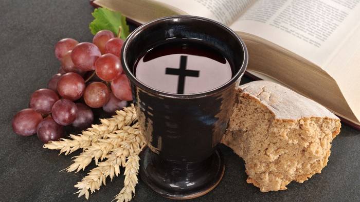 Un calice avec du vin, des raisins, du pain et un livre ouvert