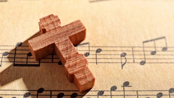 Une croix en bois repose sur des partitions musicales.