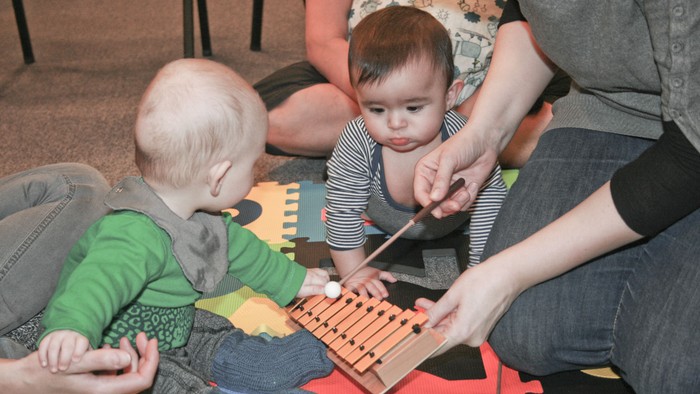 To børn spiller med marimba og en voksne.