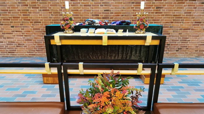 En altertavle med blomsterarrangement og lysstaker i kirke.