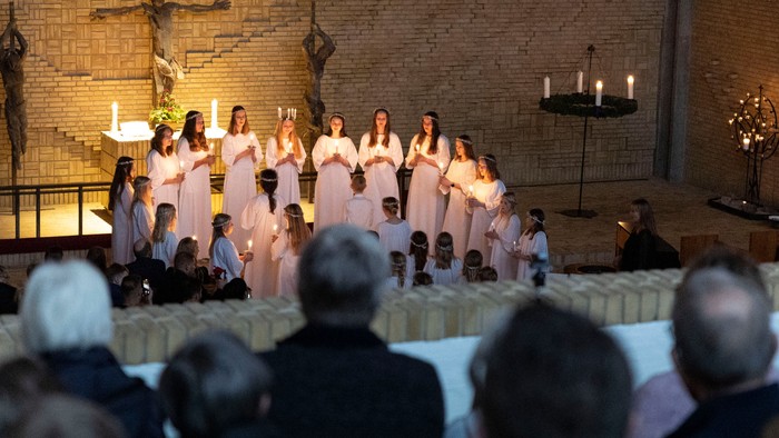 En kirkekor med kvinder i hvide klerer synger i en kirke.