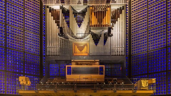 Große Kirchenorgel in einem modernen Gotteshaus mit blauen Wänden und Sitzreihen.