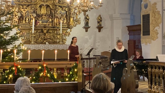 En kirke med præster og menighed under julefesten, med pynt og lys.