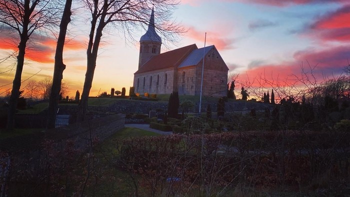 En kirke på en bakke ved solnedgang