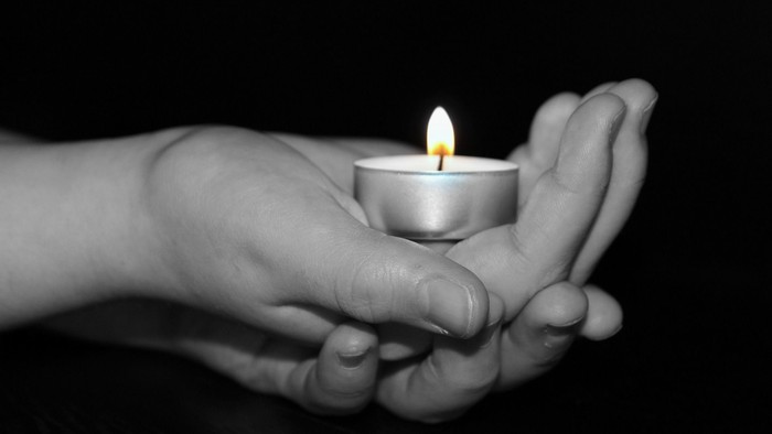En hånd holder en lyst tealight.