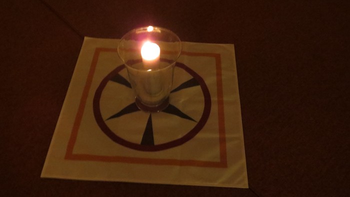 Eine leuchtende Glühbirne steht auf einem weißen Tuch mit rotem Rand.