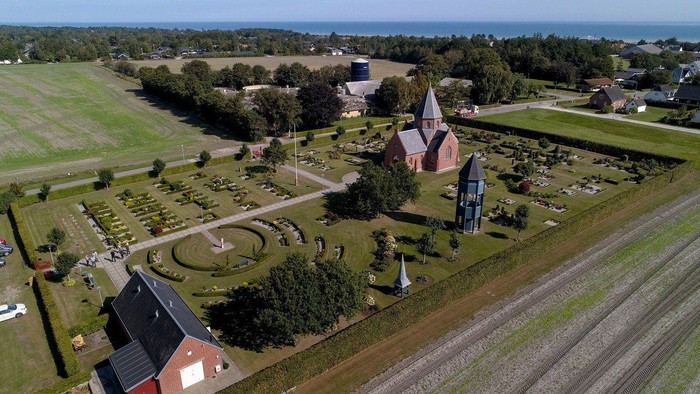 En lille kirke med gravplads i landlig omgivelse