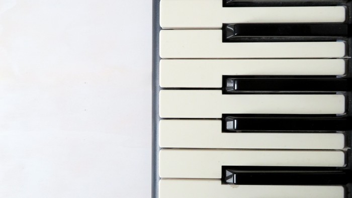 Close-up of piano keys, black and white, against a white background.