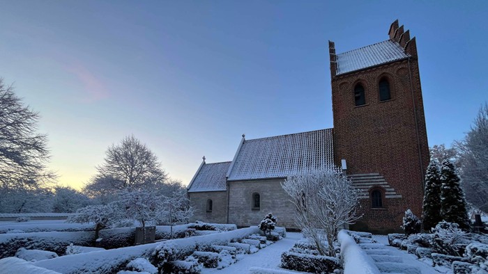 Ishøj Kirke dækket i sne på en vinterdag med blå himmel
