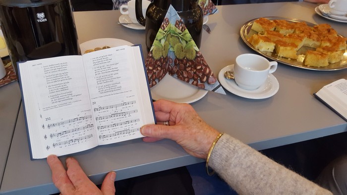 Stemningsbillede fra højskoleeftermiddag i Vejleå Kirke, hvor der bliver sunget fra højskolesangbogen, drukket kaffe og spist kage