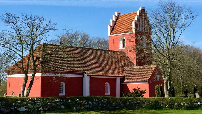 Rødt kirke med tårn og tagtegn i træ.