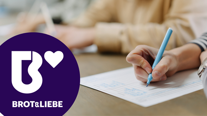 Hand, die etwas schreibt, Button mit Brot&Liebe-Logo auf dem Foto