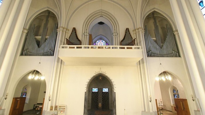 Großzügige Kirchenhalle mit hohem Gewölbe und zwei Emporen mit Orgeln.