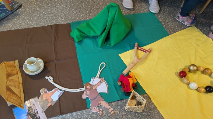 Kreatives Spielarrangement mit Stoffkulissen, Spielfiguren und kleinen Requisiten auf einem Tisch.
