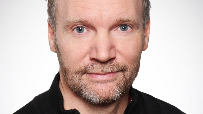 En middelalderlig mænd med kort hår og skæg, der bærer en sort trøje.