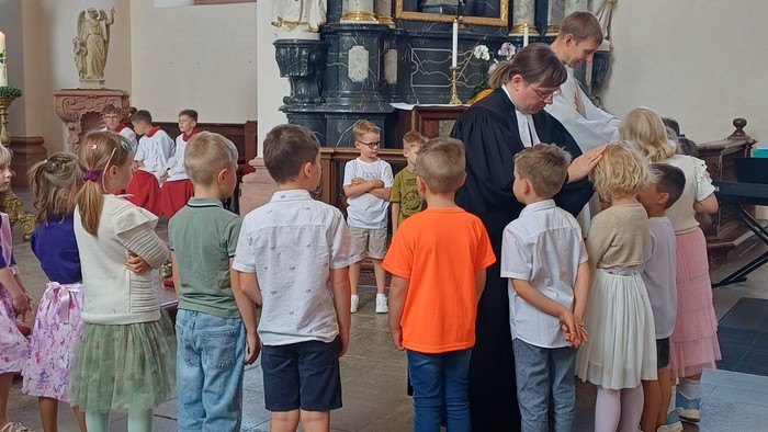 Kinder erhalten Segnungen von einem Priester während einer kirchlichen Zeremonie.