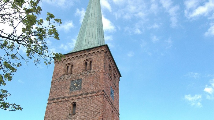 Tårn på kirke med mursten og spiret op mod himlen