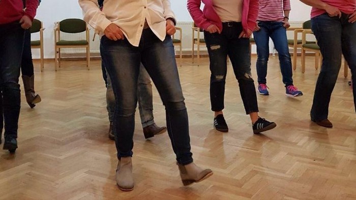 Nebeneinander stehende Menschen, die die gleichen Tanzschritte ausführen.