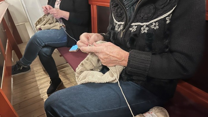 To oldere kvinder sitter og stråler med guldgul guldtråd