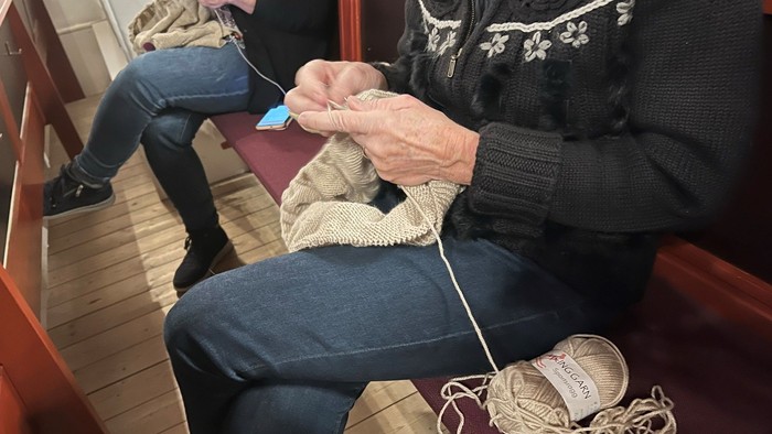 To oldere kvinder sitter og stråler med guldgul guldtråd