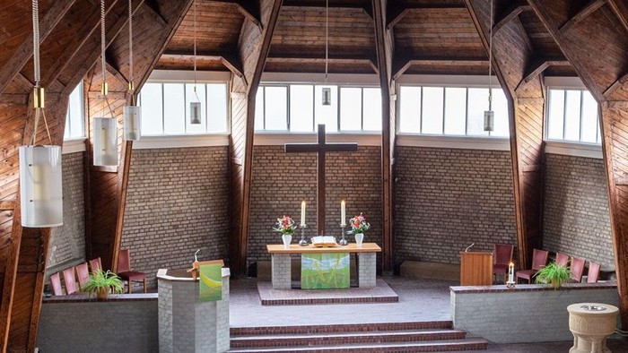 Ein moderner Wohnraum mit hohen Decken und großen Fenstern, eingerichtet mit Holz und grünen Akzenten.
