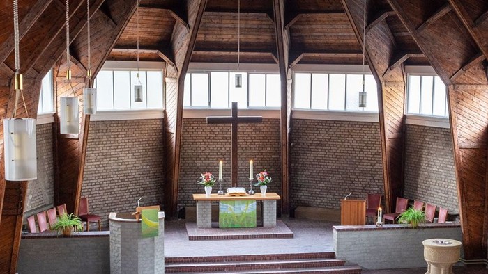 Ein moderner Wohnraum mit hohen Decken und großen Fenstern, eingerichtet mit Holz und grünen Akzenten.