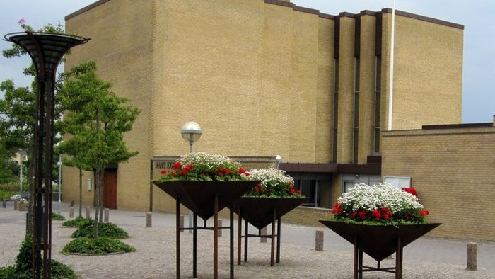 Stor gul bygning med blomsterkasser og lysekøler i forgrunden