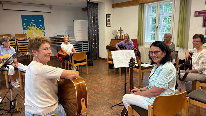 Gruppe von Musiker:innen, die in einem gemütlichen Proberaum drinnen Instrumente spielen.