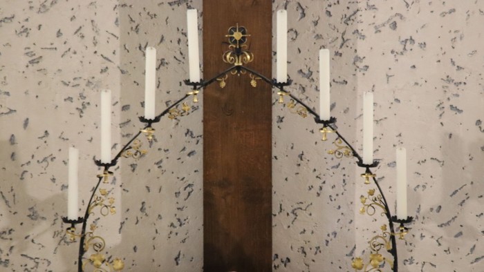 Ein hölzernes Kruzifix mit Kerzenleuchtern an der Wand