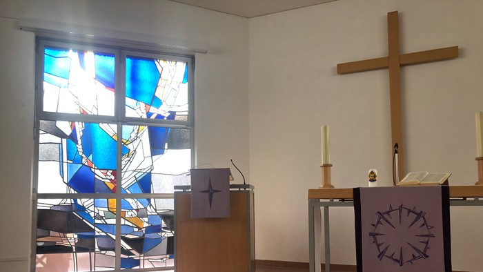 Kircheninneres mit Buntglasfenster, Kreuz und Lesepult