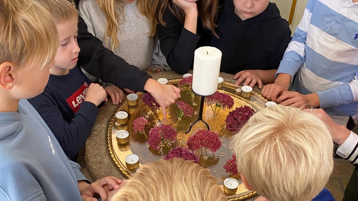 Børn samlede sig omkring et bord med en kage og lys.