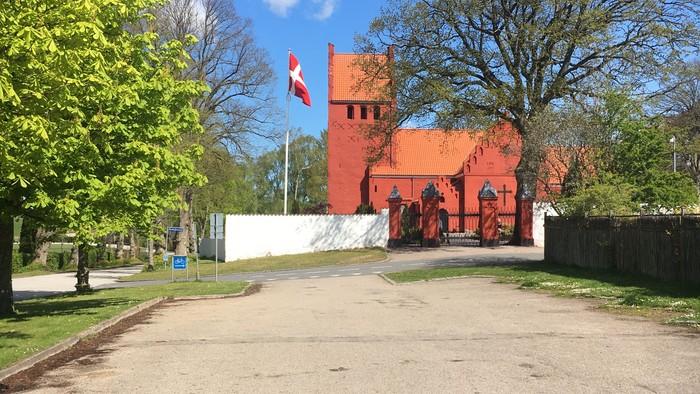En rød bygning med torn og flag ved en vej