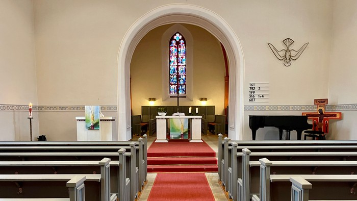 Die Kirche mit einem Altar, Buntglasfenster und Kirchenbänken
