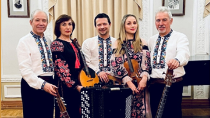 En gruppe på fire musikere poserende med strygeinstrumenter i en elegant indendørs indstilling.