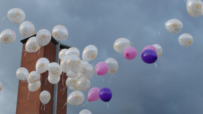 En del balloner flyver op i himlen, blå og rosa blandet med hvide