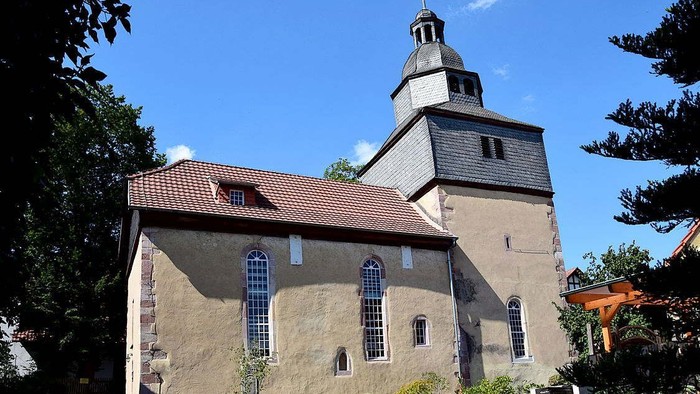 Kirchengebäude mit hohem Turm und rotem Dach unter blauem Himmel