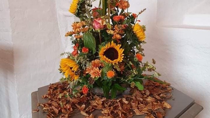 En blomsterarrangement på en altertavle med høstblomster og løv.