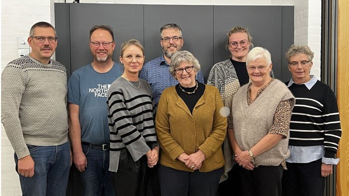 En gruppe af ni personer står sammen for en fotograf.