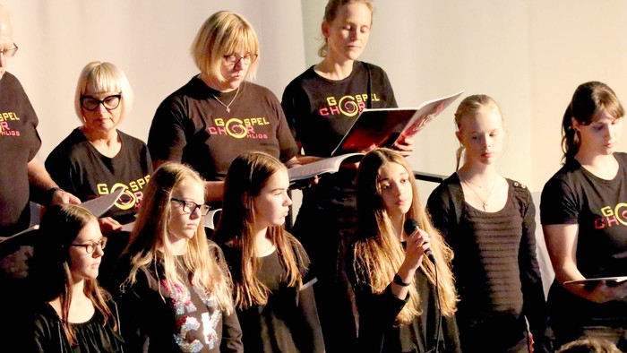 Eine Gruppe von Menschen singt gemeinsam, einige halten Notenblätter